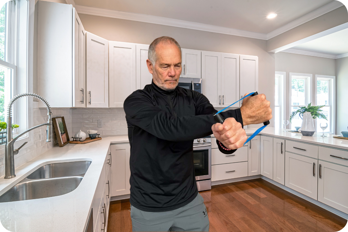 Van, founder of ShoulderBack Pro, holding both handles of the trainer in his kitchen
