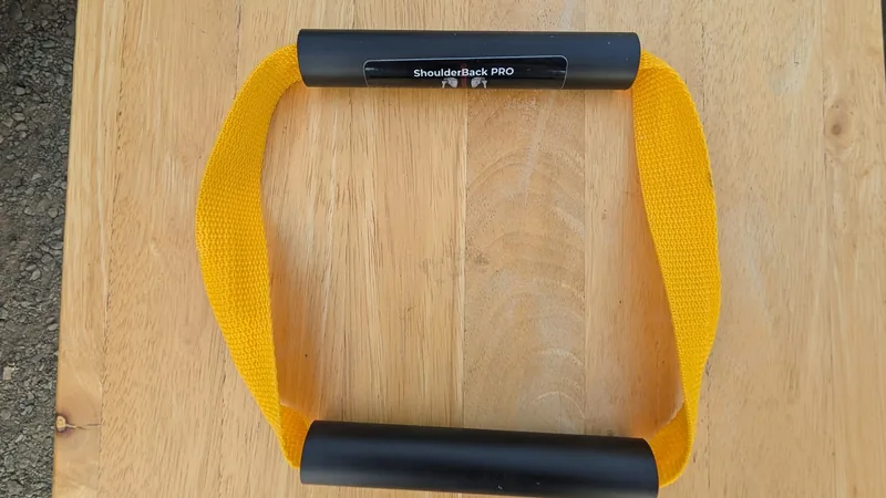 ShoulderBack Pro trainer with a yellow strap and two black handles on a light wooden table
