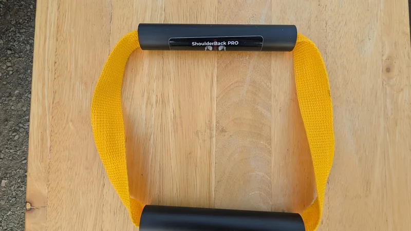 ShoulderBack Pro trainer with a yellow strap and two black handles on a light wooden table