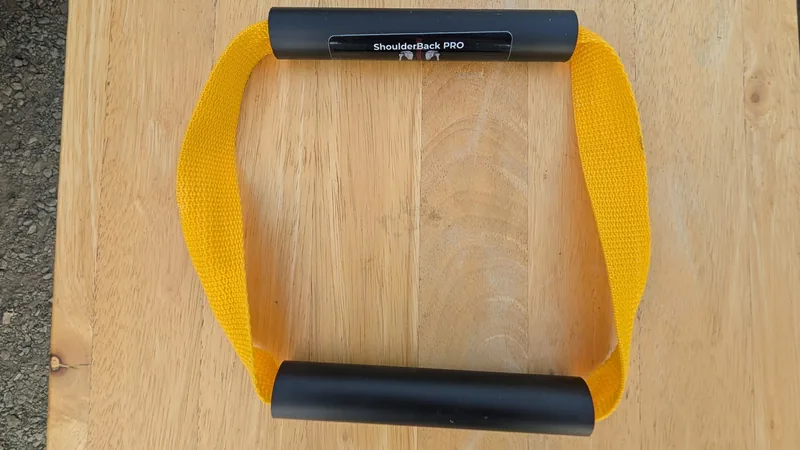 ShoulderBack Pro trainer with a yellow strap and two black handles on a light wooden table