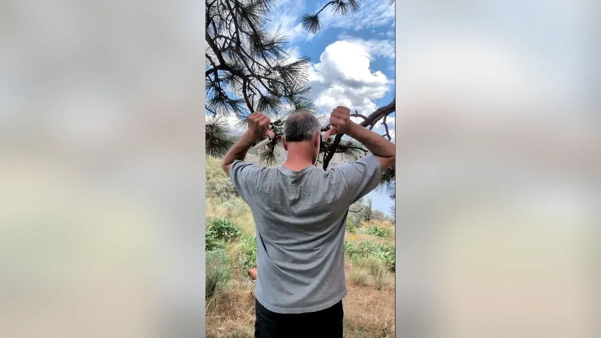 Van demonstrating the Bear Hugs Me.Jpg movement with the ShoulderBack Pro outdoors — a frame from the routine video