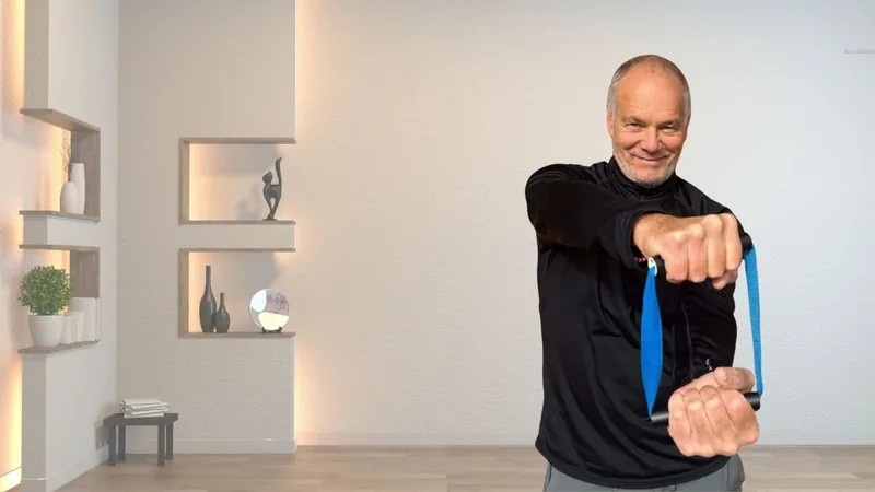 Van, founder of ShoulderBack Pro, standing in a bright room pulling the trainer across his body with both hands