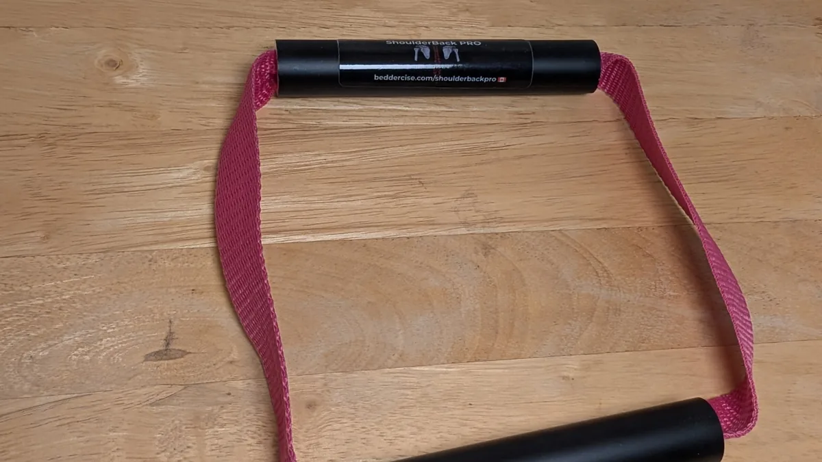 ShoulderBack Pro trainer with a pink strap on a wooden table, photographed at an angle