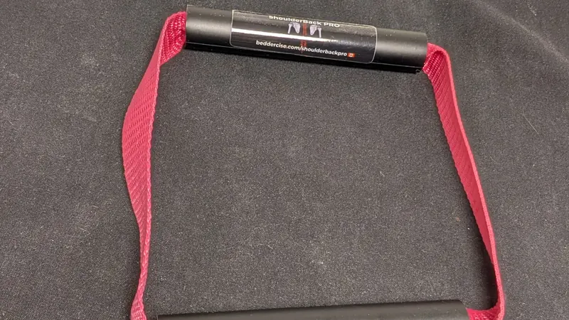 ShoulderBack Pro trainer with a burgundy strap resting on a dark cushion