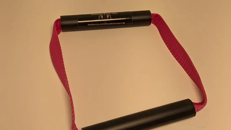 ShoulderBack Pro trainer with a pink strap on a white desk under warm indoor light