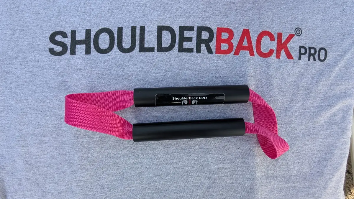 ShoulderBack Pro trainer with a pink strap resting on a grey ShoulderBack Pro shirt