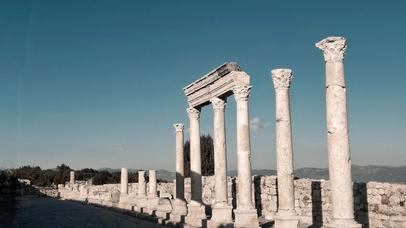 Weathered stone columns and an open training ground at dawn, with no people visible