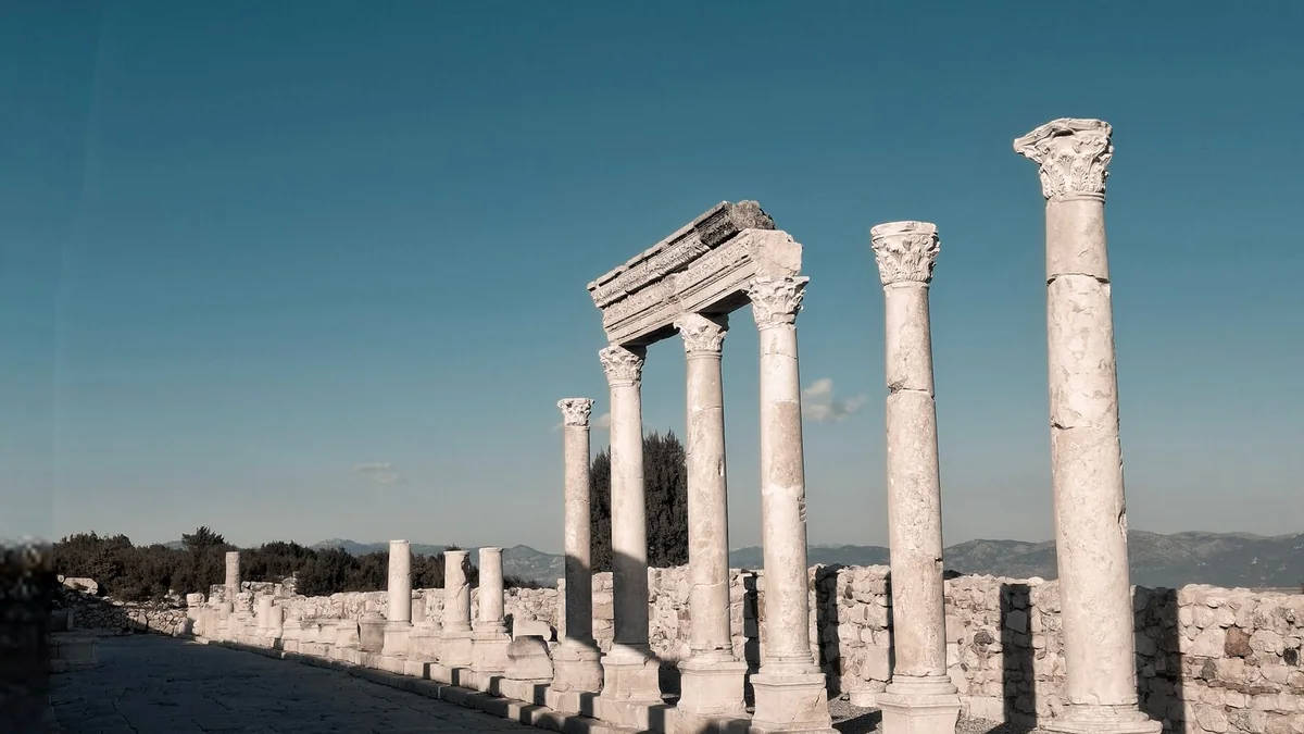Weathered stone columns and an open training ground at dawn, with no people visible