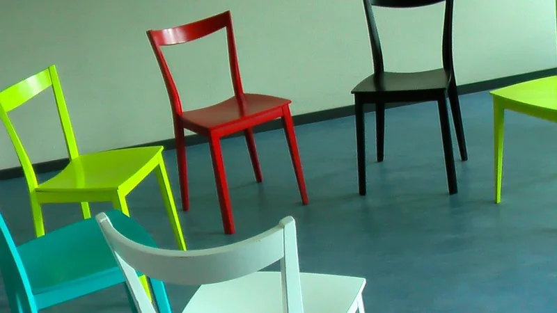 A bright community room with chairs arranged in a circle and a window with daylight, no people visible