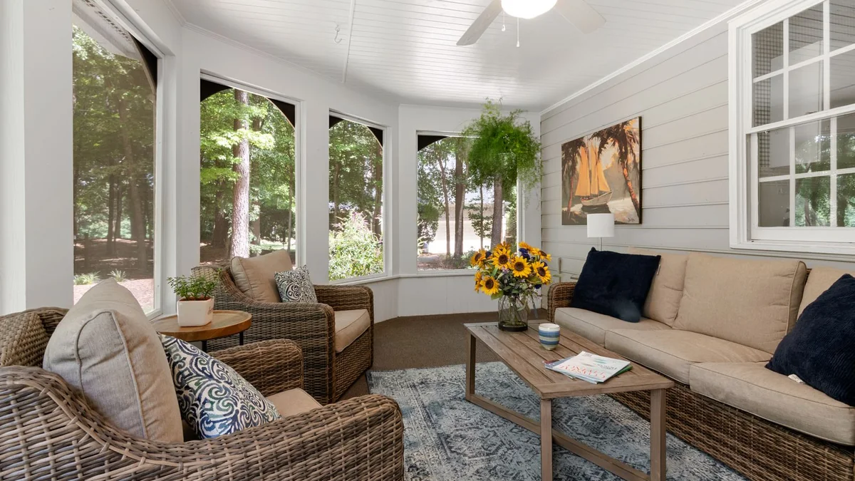 A bright sunroom with several armchairs and a small table with a water jug, set up for a gentle group activity.