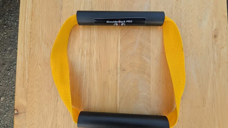 ShoulderBack Pro trainer with a yellow strap and two black handles on a light wooden table