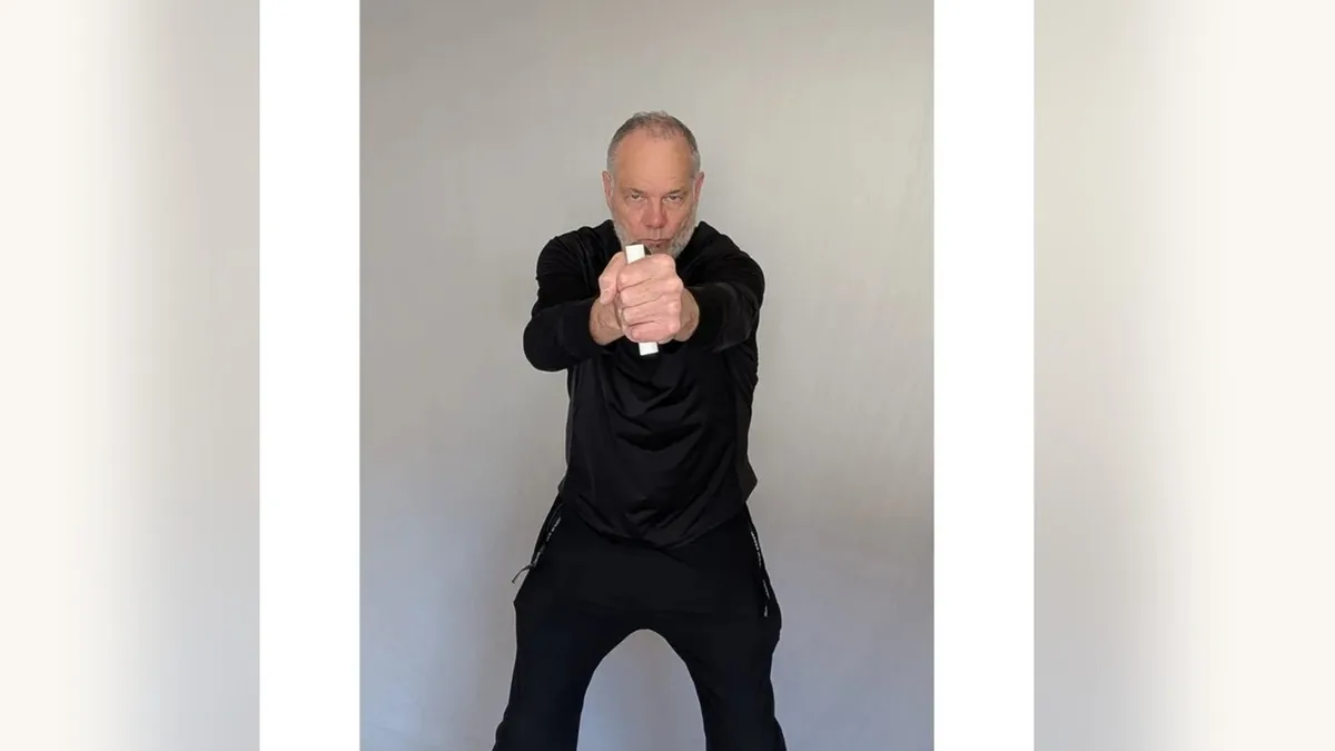Van gripping both ShoulderBack Pro handles in front of his chest, one in each fist