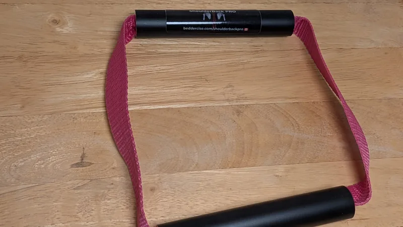 ShoulderBack Pro trainer with a pink strap on a wooden table, photographed at an angle