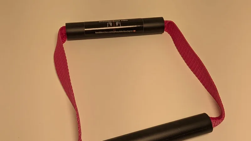 ShoulderBack Pro trainer with a pink strap on a white desk under warm indoor light