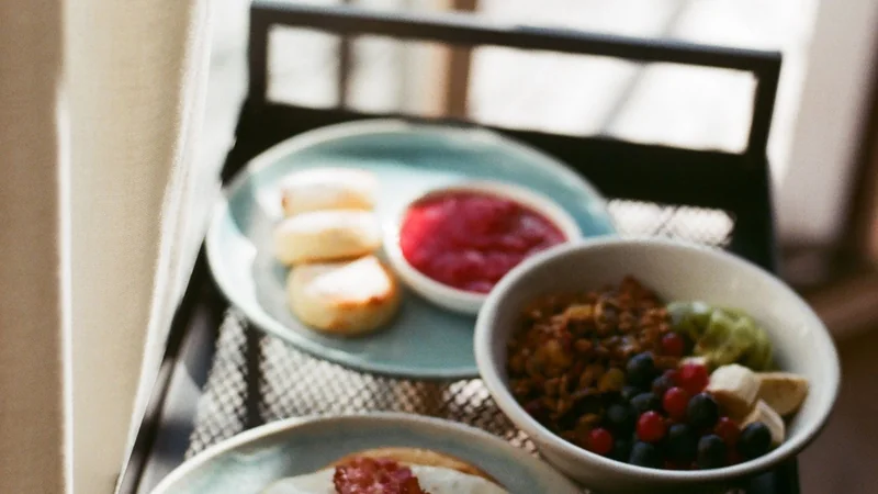 A simple breakfast plate with eggs, plain yogurt and berries on a wooden table, bright morning light, no people