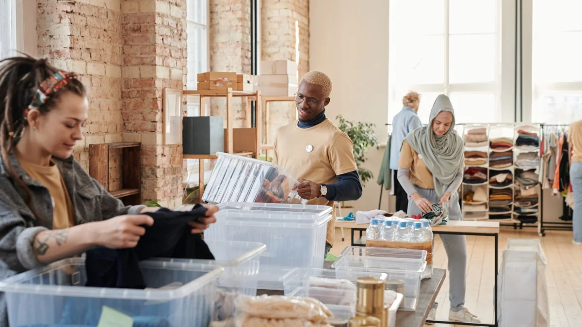 Volunteers sorting donated items at a community table in a bright room, one person seated and one standing