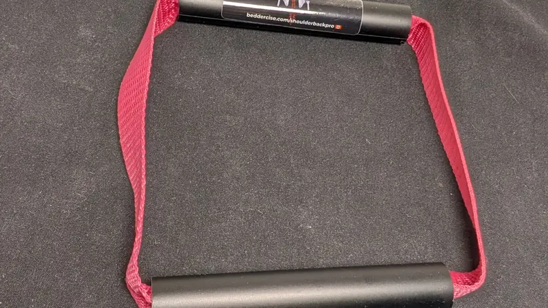 ShoulderBack Pro trainer with a burgundy strap resting on a dark cushion