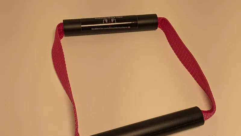 ShoulderBack Pro trainer with a pink strap on a white desk under warm indoor light
