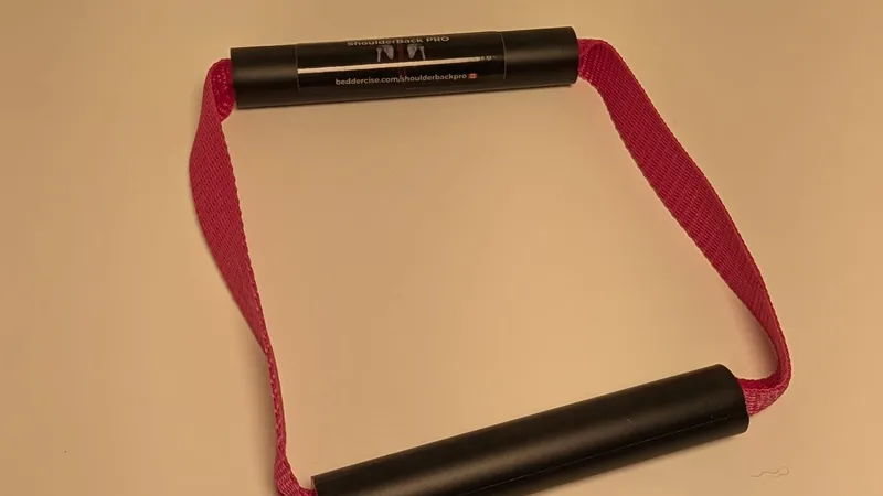 ShoulderBack Pro trainer with a pink strap on a white desk under warm indoor light